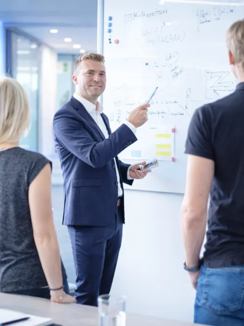 Berater erläutert einem Team Ideen am Whiteboard
